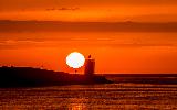 Immagine terra Mare con lembo di terra e faro al tramonto