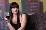 Immagine vino rosso Ragazza seduta su divano con bicchiere di vino rosso in mano