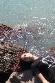 Immagine ragazza triste Ragazza triste sdraiata su un masso al mare in Spagna
