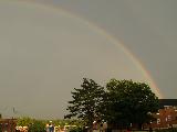 Semiarco di arcobaleno che parte dietro una casa