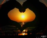 Immagine fatto Sole al tramonto attraverso un dolce cuore fatto con le mani
