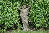 Statua di ragazza che si tocca simpaticamente la testa in giardino
