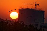 Tramonto con sole gigante e fabbrica in costruzione