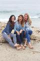 Tre belle ragazze sedute sulla spiaggia che sorridono